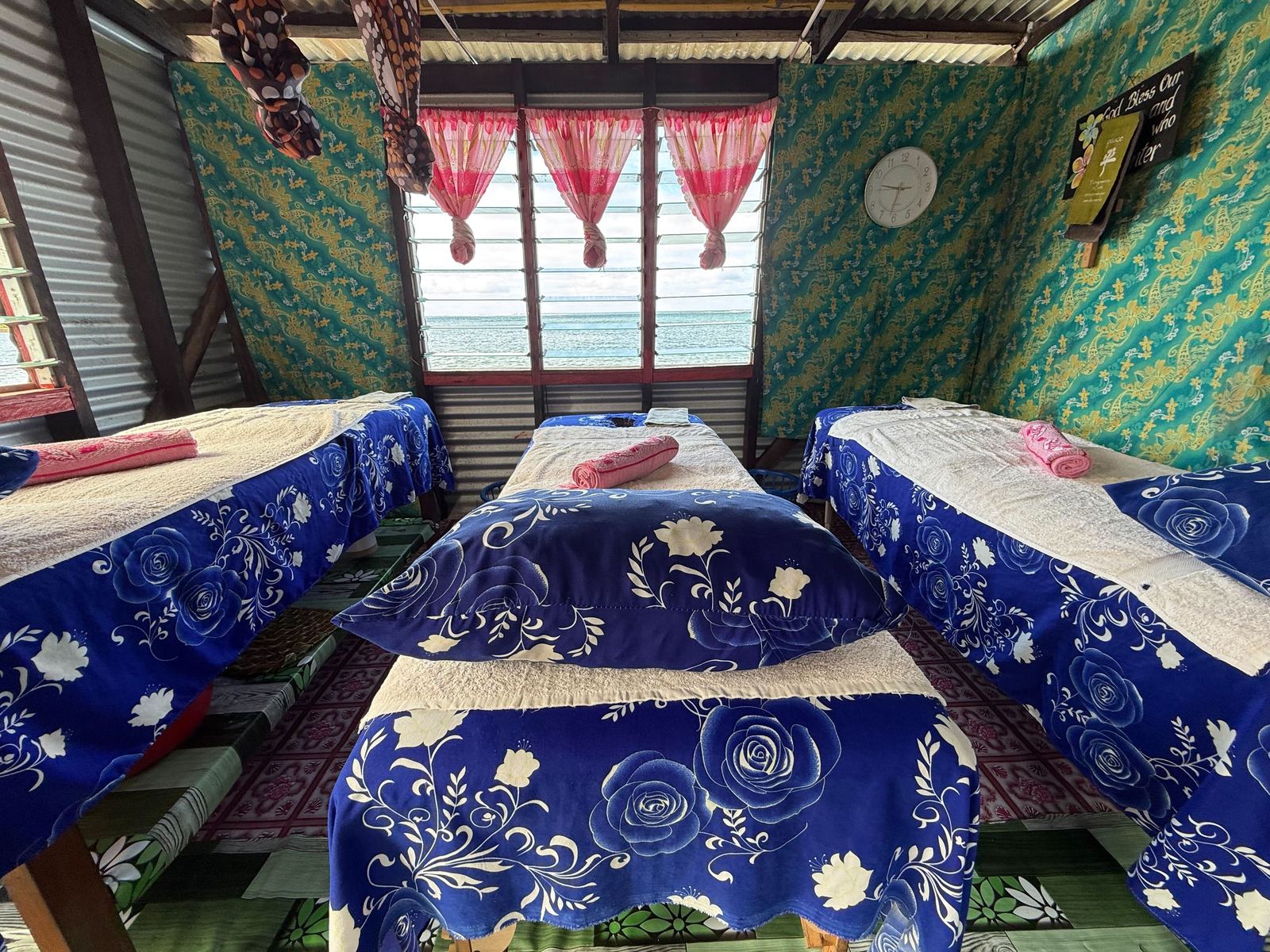 Three massage beds with blue covers and pink towels